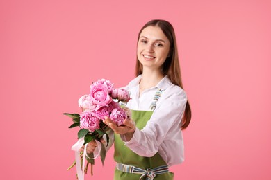 Photo of Florist with beautiful peonies on pink background