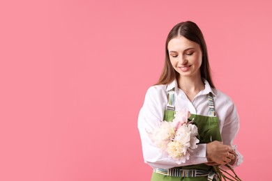 Photo of Florist with beautiful peonies on pink background, space for text