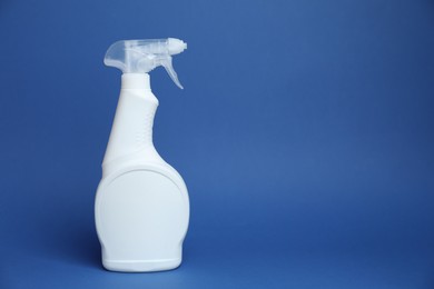 Photo of White spray bottle of cleaning product on blue background, space for text