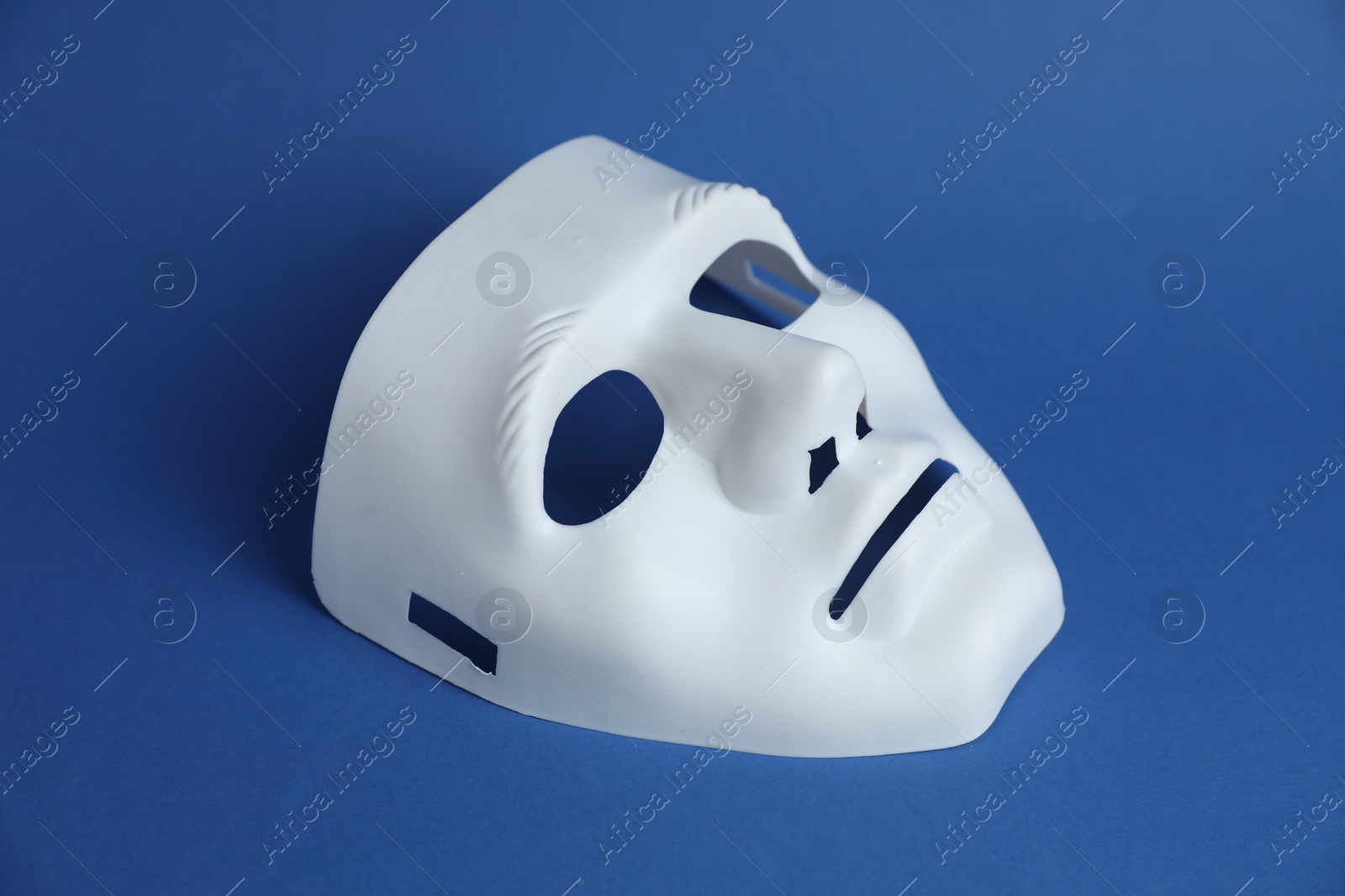 Photo of One white theatre mask on blue background