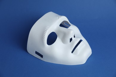 Photo of One white theatre mask on blue background