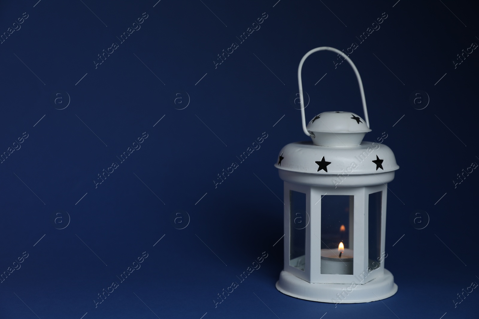 Beautiful white decorative lantern with burning candle on blue background, space for text Photo of Beautiful white decorative lantern with burning candle on blue background, space for text