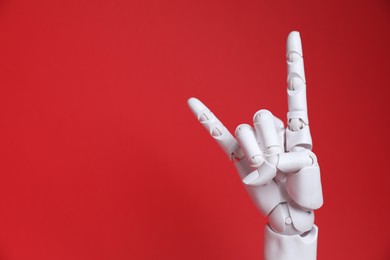 Photo of White mannequin hand making rock gesture on red background, space for text