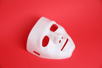 Photo of One white theatre mask on red background, above view