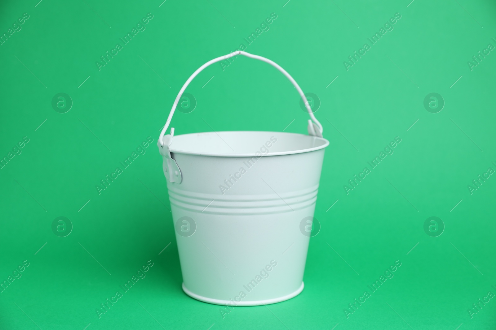 Photo of One white metal bucket on green background