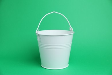 Photo of One white metal bucket on green background