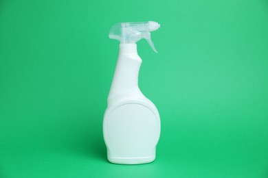 Photo of White spray bottle of cleaning product on green background