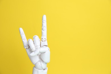 Photo of White mannequin hand making rock gesture on yellow background, space for text