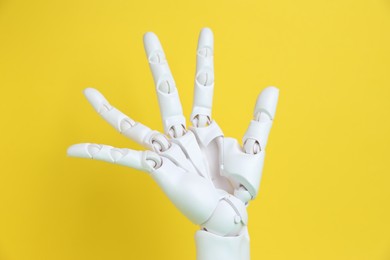 Photo of One white mannequin hand on yellow background