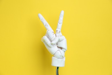 Photo of White mannequin hand showing peace sign on yellow background