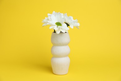 Photo of Beautiful white chrysanthemum flowers in vase on yellow background