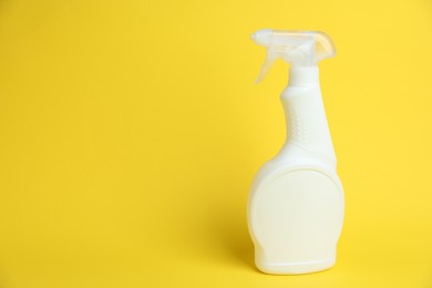Photo of White spray bottle of cleaning product on yellow background, space for text