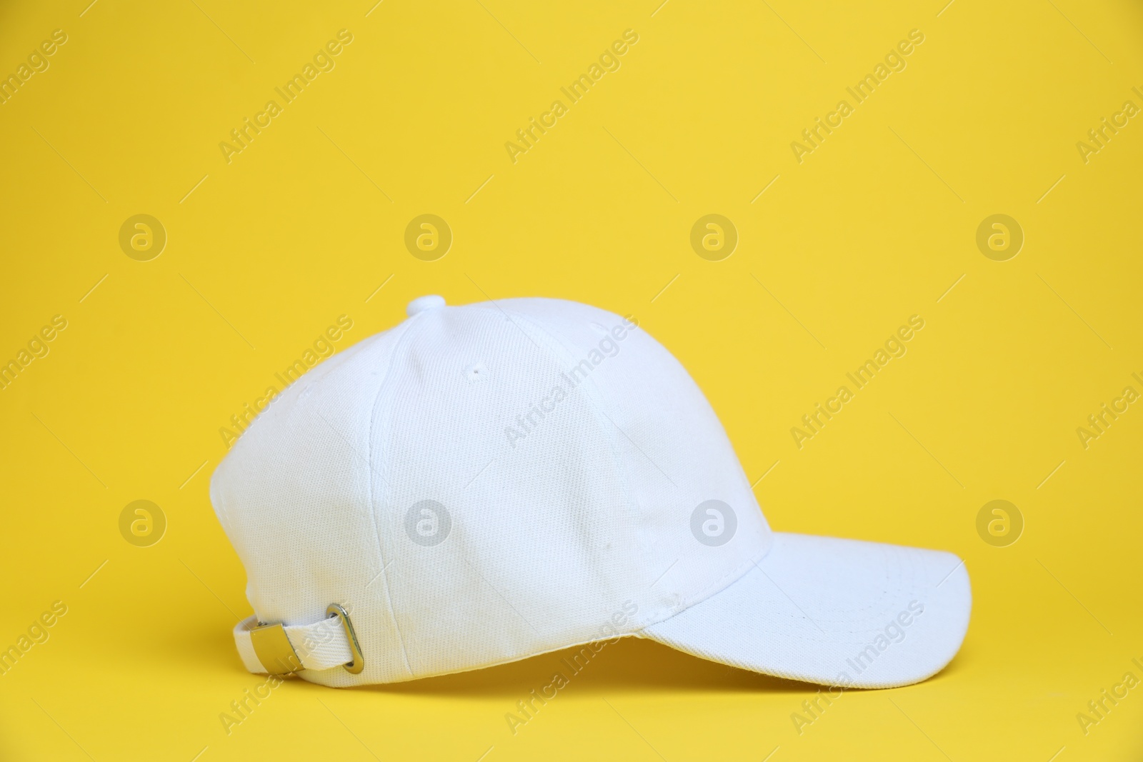 One white baseball cap on yellow background Photo of One white baseball cap on yellow background