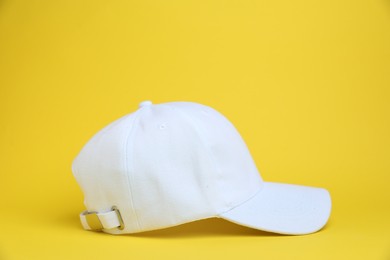 Photo of One white baseball cap on yellow background