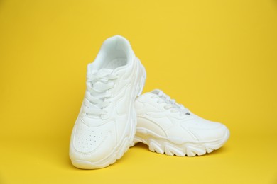 Photo of Pair of white sneakers on yellow background