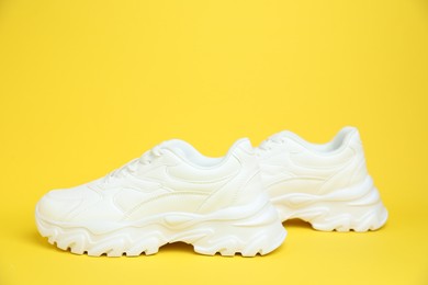 Photo of Pair of white sneakers on yellow background