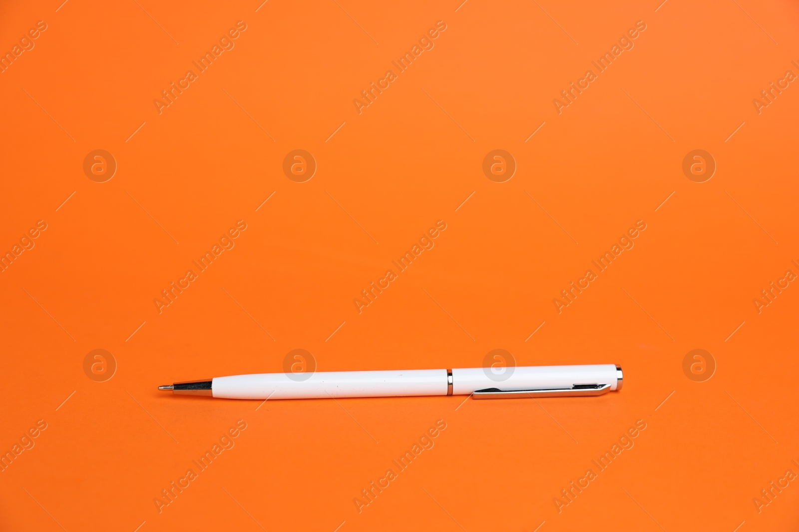 Photo of One white pen on orange background, space for text