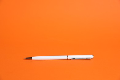 Photo of One white pen on orange background, space for text
