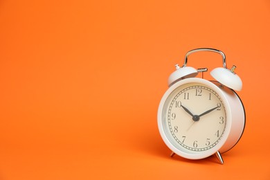 Photo of One white alarm clock on orange background, space for text