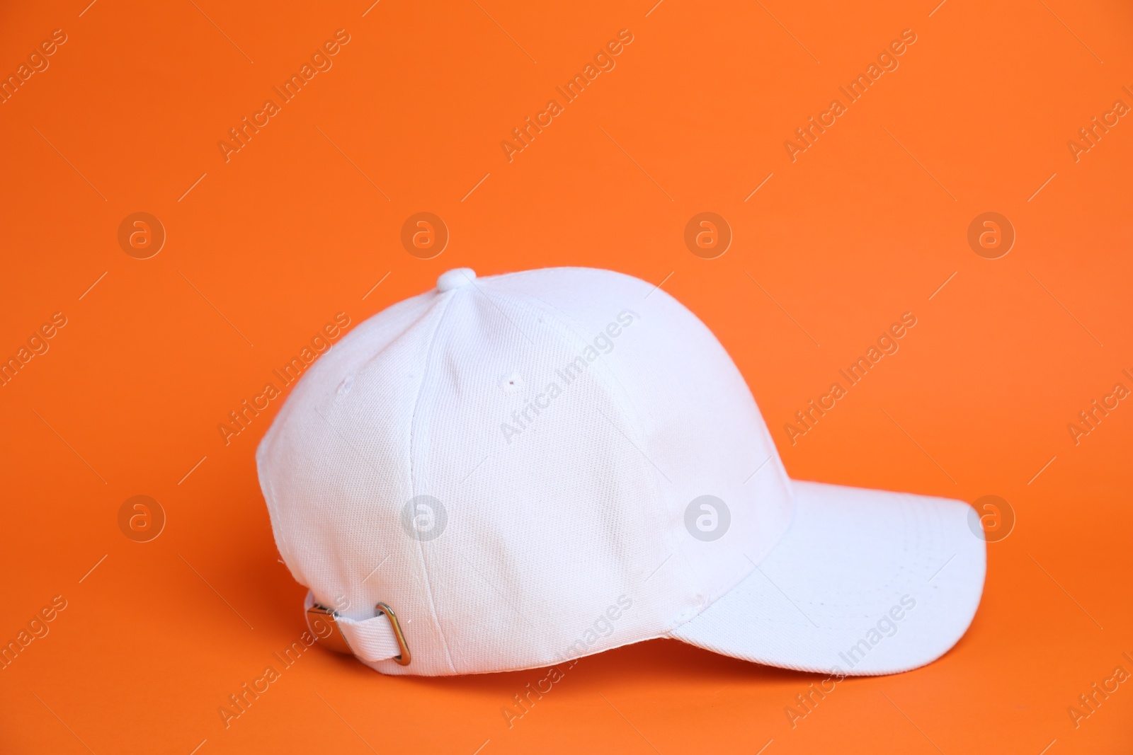 Photo of One white baseball cap on orange background