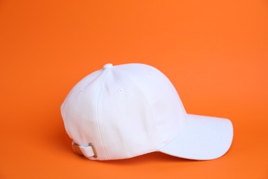 Photo of One white baseball cap on orange background
