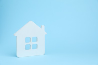 Photo of One white house model on light blue background, space for text