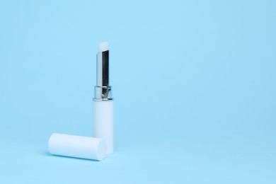 Photo of One white lipstick on light blue background, space for text