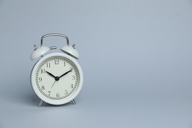 Photo of One white alarm clock on light grey background, space for text