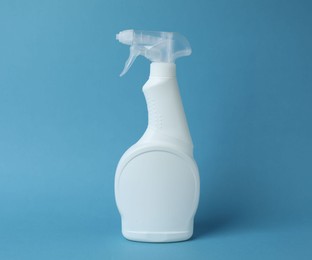 Photo of White spray bottle of cleaning product on light blue background