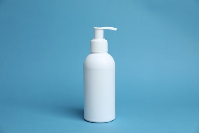 Photo of One white bottle of cosmetic product on light blue background