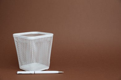 Photo of White pen and holder on brown background, space for text