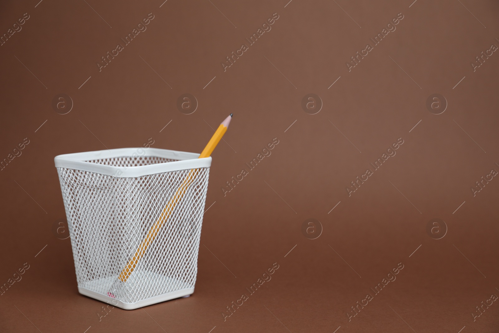 Pencil in white holder on brown background, space for text Photo of Pencil in white holder on brown background, space for text