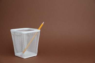 Photo of Pencil in white holder on brown background, space for text