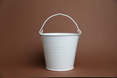 Photo of One white metal bucket on brown background