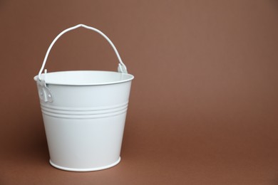 Photo of One white metal bucket on brown background, space for text