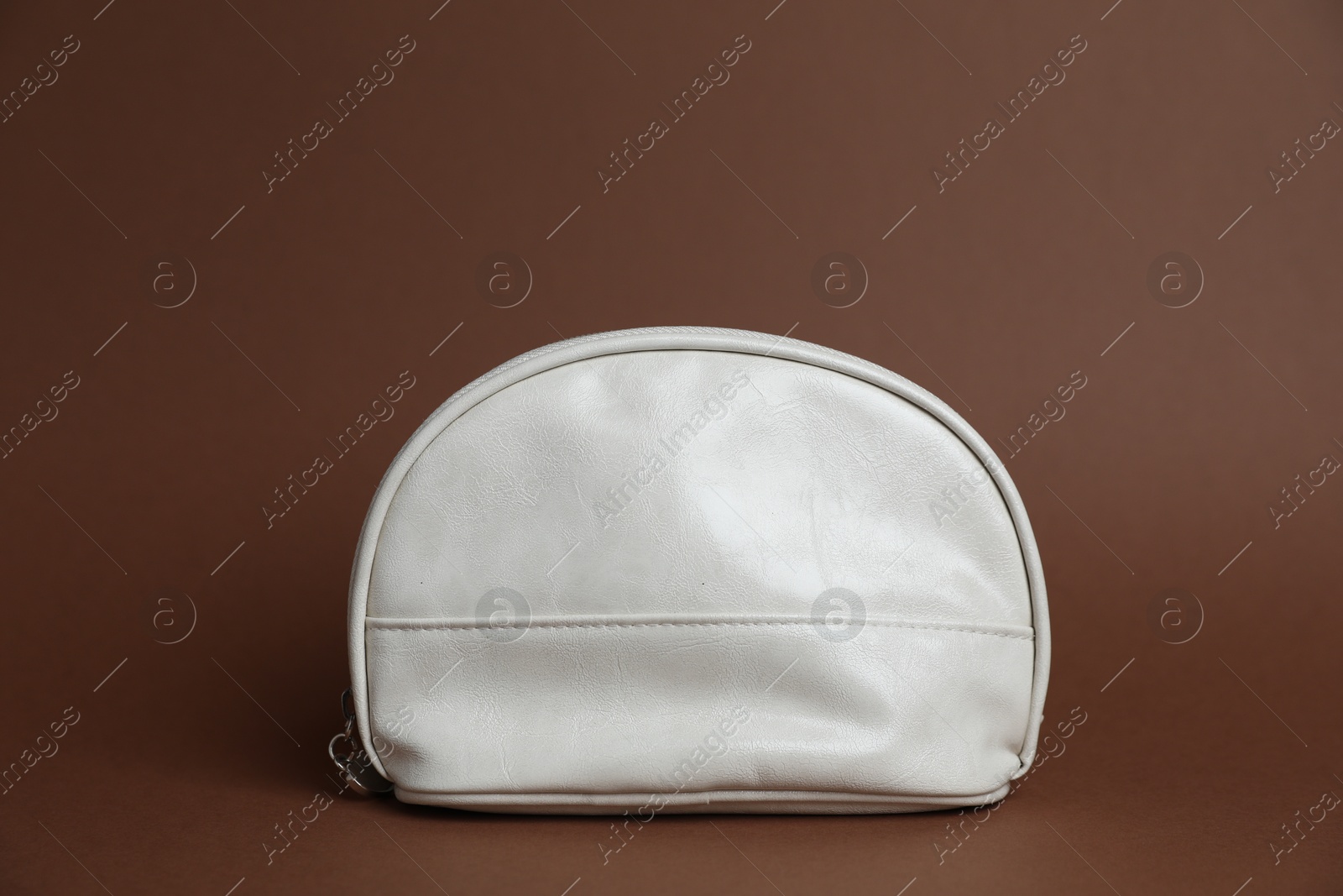 One white cosmetic bag on brown background Photo of One white cosmetic bag on brown background