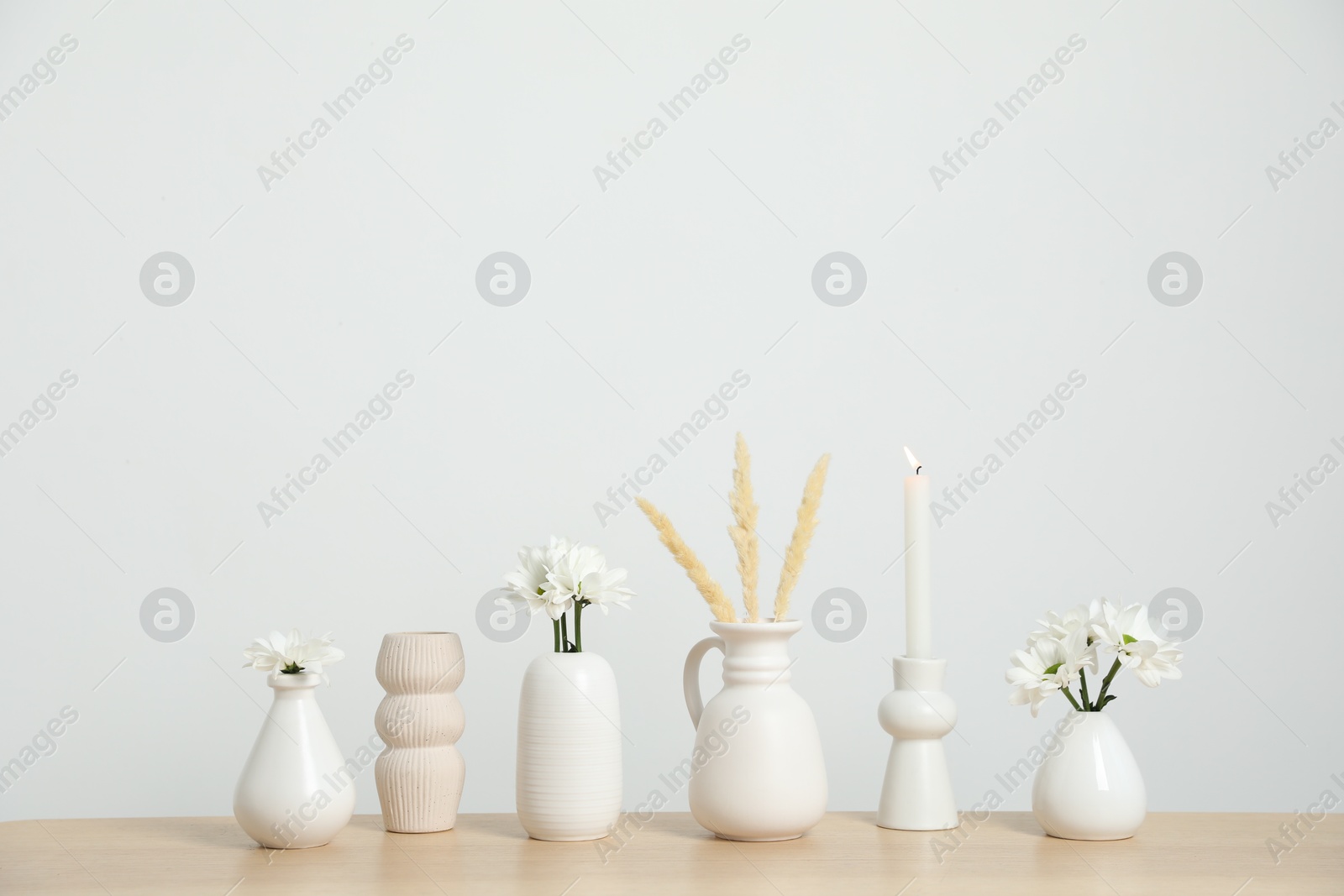 Different decor on wooden table near white wall indoors Photo of Different decor on wooden table near white wall indoors