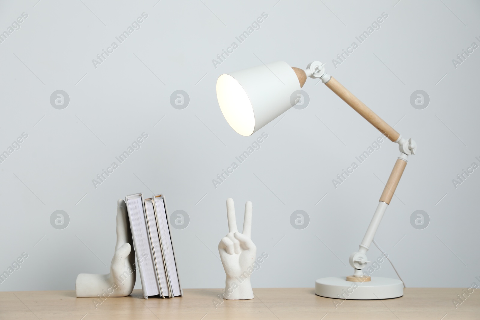 Different decor and lamp on wooden table near white wall indoors Photo of Different decor and lamp on wooden table near white wall indoors