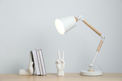 Photo of Different decor and lamp on wooden table near white wall indoors