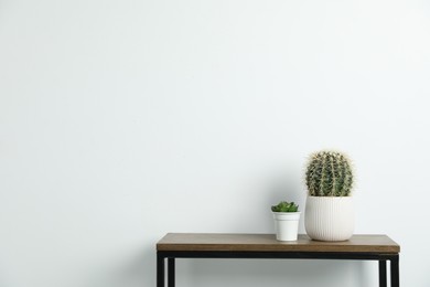Photo of Beautiful floral decor on wooden table near white wall indoors, space for text