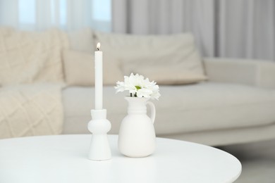 Photo of Beautiful chrysanthemum flowers in vase and burning candle on white table indoors