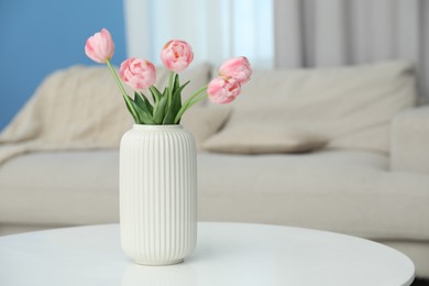Photo of Beautiful tulip flowers in vase on white table indoors, space for text