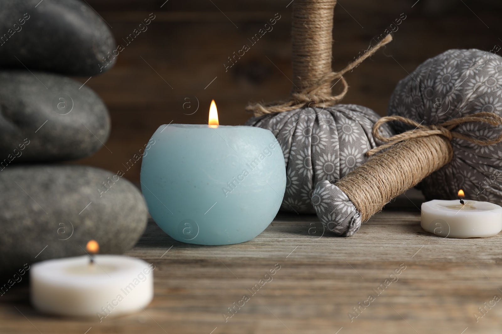 Spa stones, herbal bags and burning candles on wooden table, closeup Photo of Spa stones, herbal bags and burning candles on wooden table, closeup