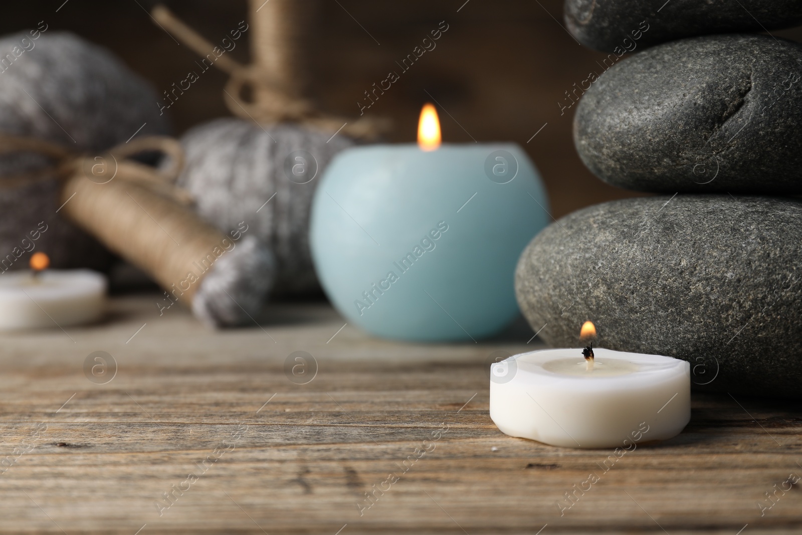 Spa stones, herbal bags and burning candles on wooden table, closeup Photo of Spa stones, herbal bags and burning candles on wooden table, closeup
