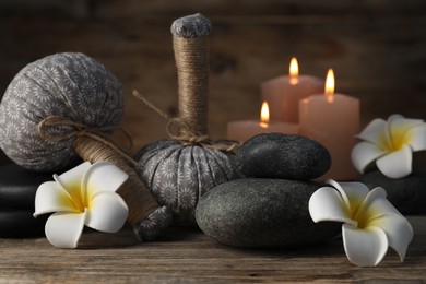 Photo of Composition with herbal bags and spa stones on wooden table, closeup