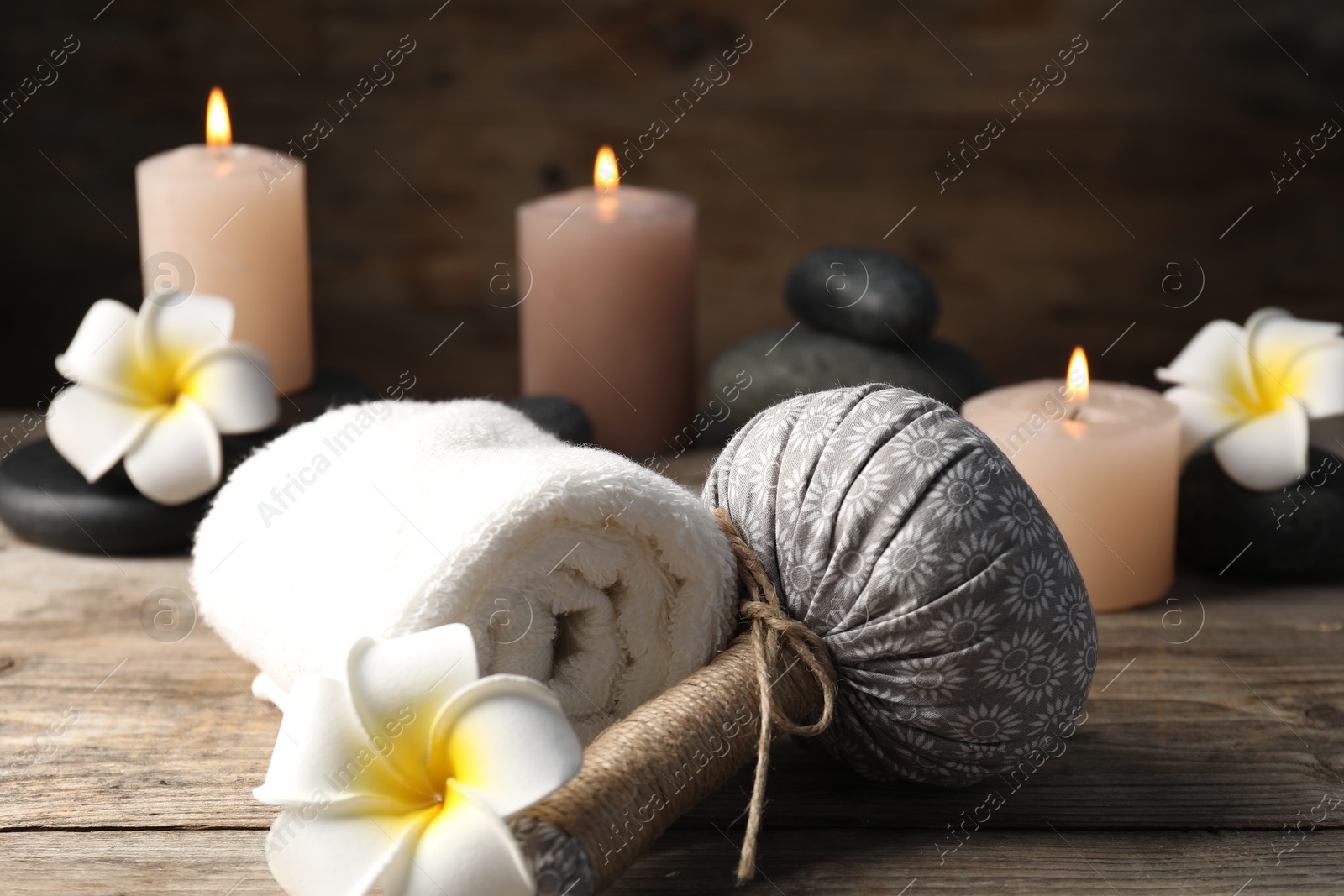 Composition with herbal bag, towel and spa stones on wooden table, closeup Photo of Composition with herbal bag, towel and spa stones on wooden table, closeup