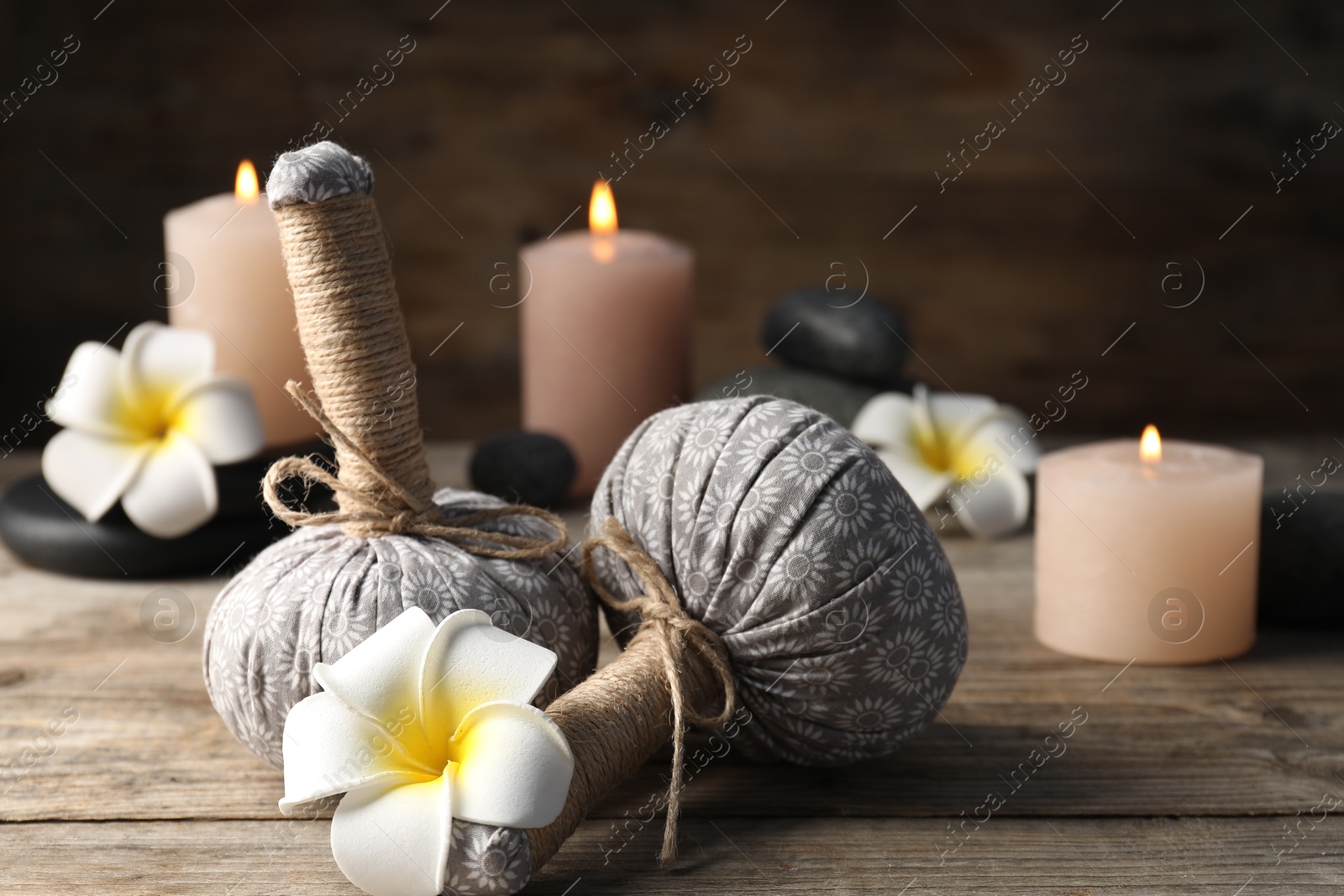 Composition with herbal bags and spa stones on wooden table, closeup Photo of Composition with herbal bags and spa stones on wooden table, closeup
