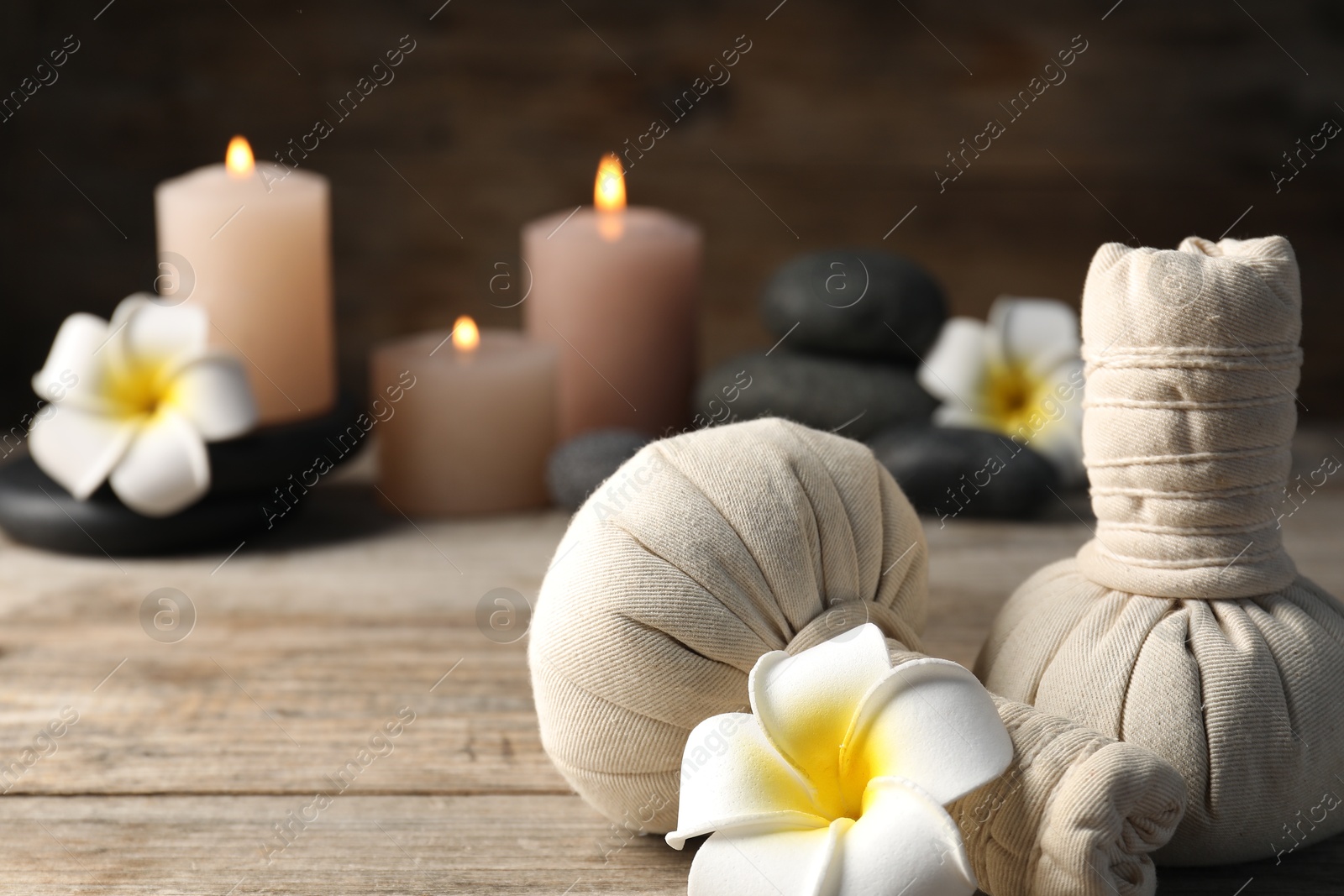 Composition with herbal bags and spa stones on wooden table, closeup Photo of Composition with herbal bags and spa stones on wooden table, closeup