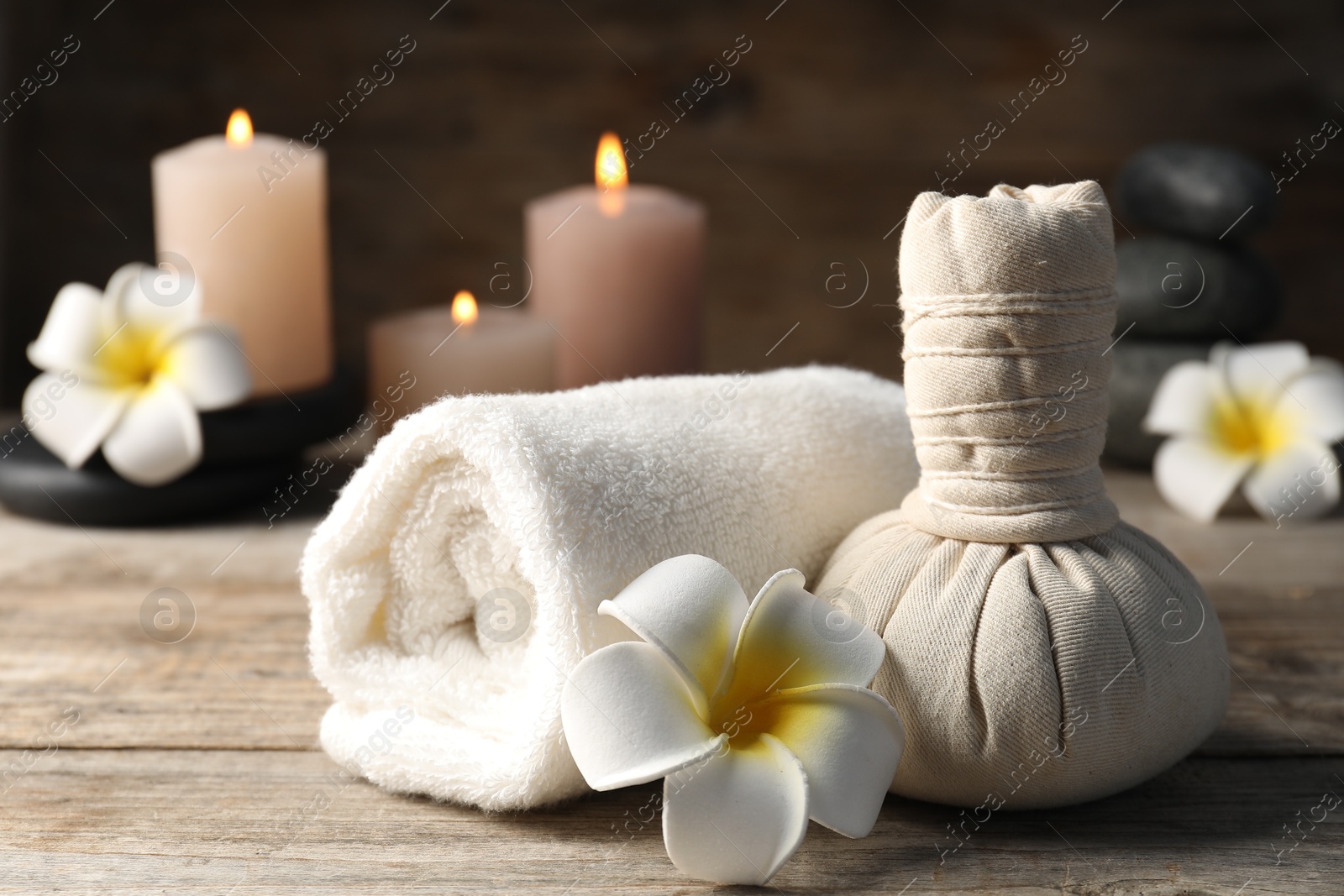 Composition with herbal bag, towel and spa stones on wooden table, closeup Photo of Composition with herbal bag, towel and spa stones on wooden table, closeup