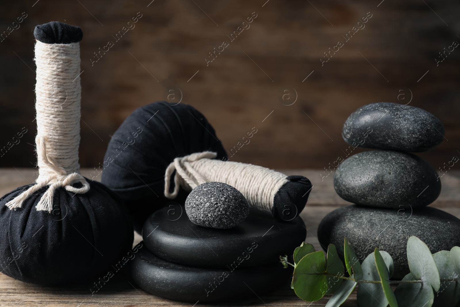 Composition with herbal bags and spa stones on wooden table, closeup Photo of Composition with herbal bags and spa stones on wooden table, closeup